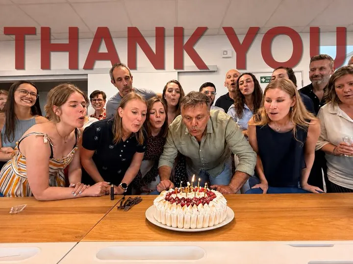 The MyData-TRUST team gathered around a birthday cake in front of a THANK YOU wall